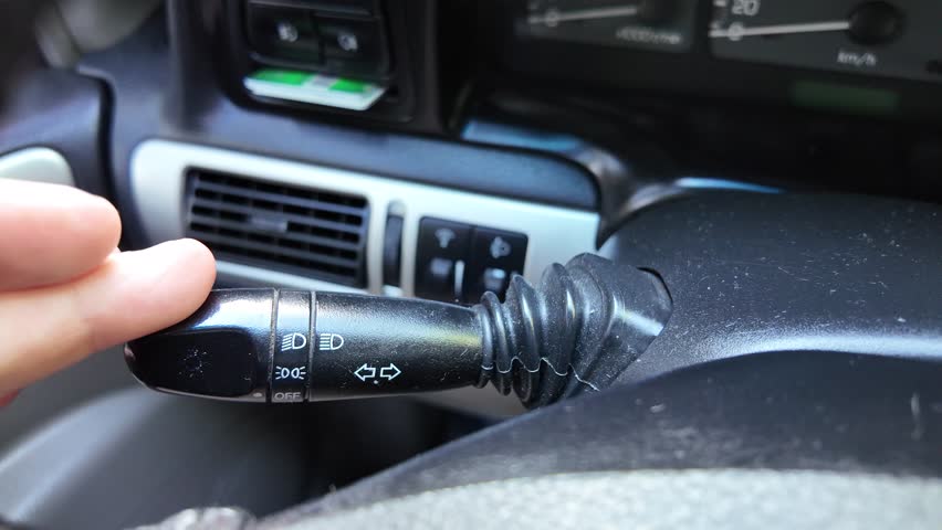 The driver turns on the turn signal. The driver shifts the lever. The person controls the car.