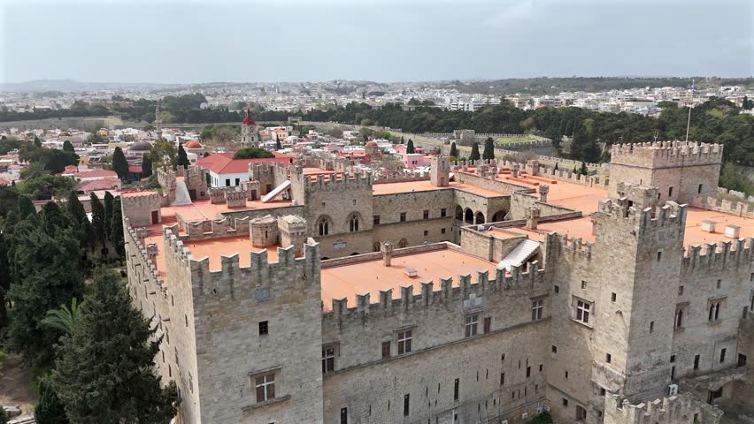 Aerial backwards from The Grand Master's Palace of the Knights at Rhodes Island on a sunny day. Castle walls surrounded by the trees.
