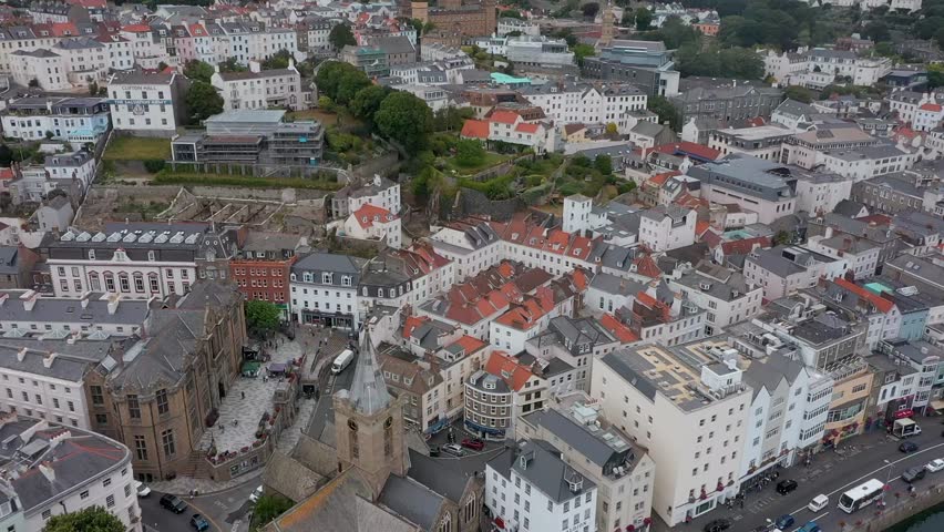 Drone showcases classic stone houses and narrow streets of Guernsey’s historic area.