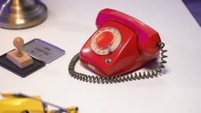A close-up of a delicate hand reaching for the rotary dial of a bright red vintage phone. Placed on a clean white desk, this retro scene evokes classic communication in a stylish minimalist setting - Powered by Shutterstock - Get 15% off with code: PIKWIZARD15