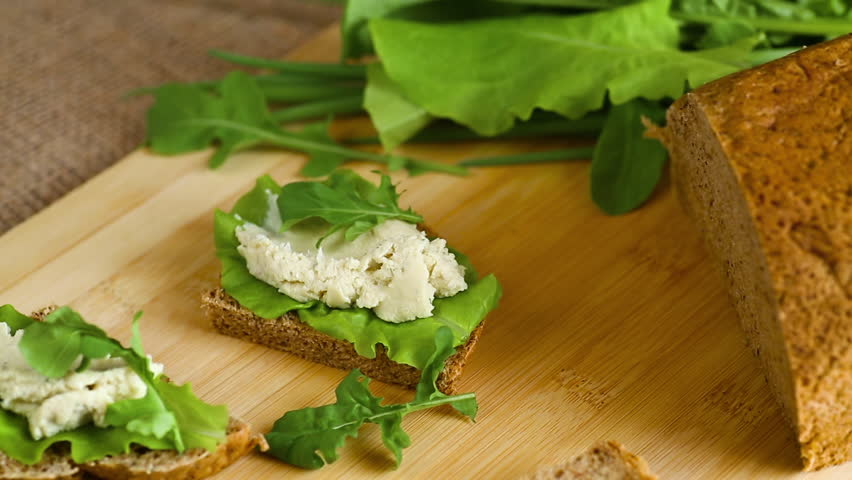 Vegetarian snack with cheese spread and fresh leaves
