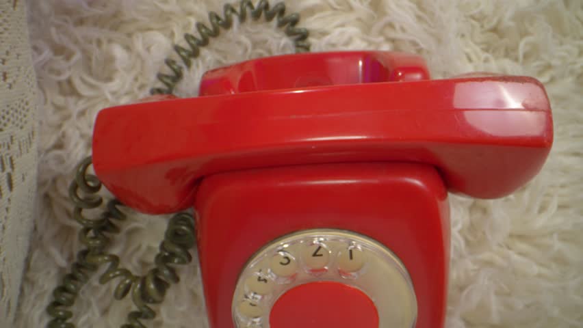 Top-down view of a woman holding a classic red rotary phone to her ear, dressed casually in green and sitting on a plush rug, creating a nostalgic yet modern home ambiance with vintage aesthetics