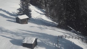 Two small rustic cabins are nestled on a snowy hillside, framed by dense pine forest. Aerial view, parallax shot. - Powered by Shutterstock - Get 15% off with code: PIKWIZARD15
