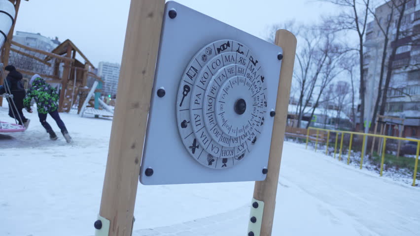 Colorful outdoor puzzle with spinning discs displays syllables for word-making. Preschoolers enjoy playful learning in fun environment