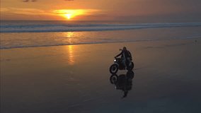 Couple rides along beach on motorcycle on a tropical island. Man and woman in road trip on a bike on the coast. Male and female ride a scooter on the ocean or sea shore. Bali Indonesia, sunset. - Powered by Shutterstock - Get 15% off with code: PIKWIZARD15