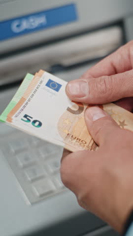 Close Up of Unrecognizable Man, Businessman Counting Euro Bills After Withdrawing Cash Money Transaction from ATM Machine. Banking Services, Cash Withdrawal, Financial Operations. Vertical Shot.