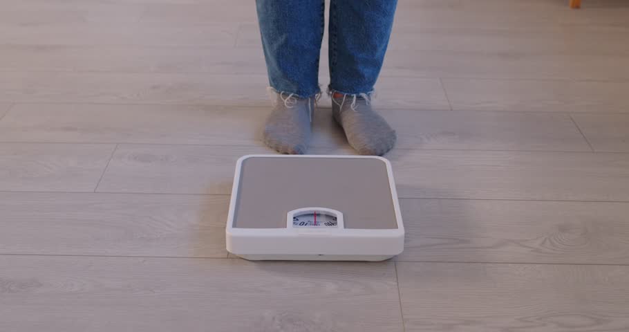 Close up feet of big chubby woman doing weight measurement on floor scales, getting result, doing regular check, monitoring body mass, loss of weight, planning slimming, dreaming of weight loss