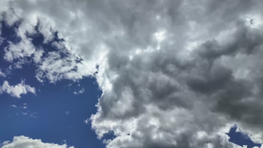 a time-lapse, low angle view, of a stormy sky with evolving darkening clouds under a deep blue sky.