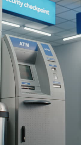 ATM Machine in Airport Terminal: Man Pressing Buttons on ATM Keypad, Entering PIN Code for Money Withdrawal Operation, Taking Cash. Cash Machine, Banking Services and Transactions. Vertical Shot.