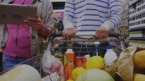Couple pushing grocery cart scanning tablet analyzing line charts forecasting retail trends. Retail, shopping, aisle, consumer, market, analysis, technology - Powered by Shutterstock - Get 15% off with code: PIKWIZARD15