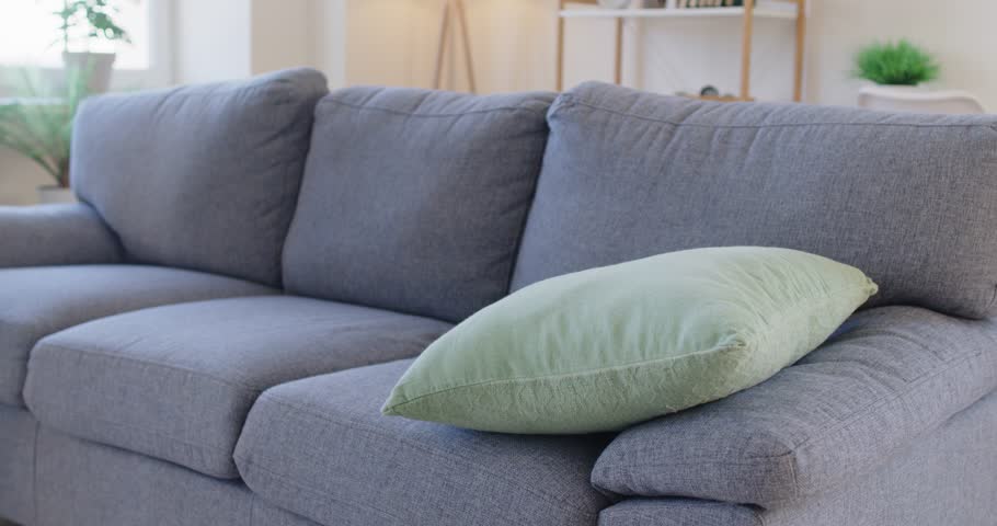 Tired man walking into cozy living room and collapsing onto soft sofa. Exhausted guy lying on couch, showing signs of weariness, resting and seeking comfort and relaxation after long and draining day.