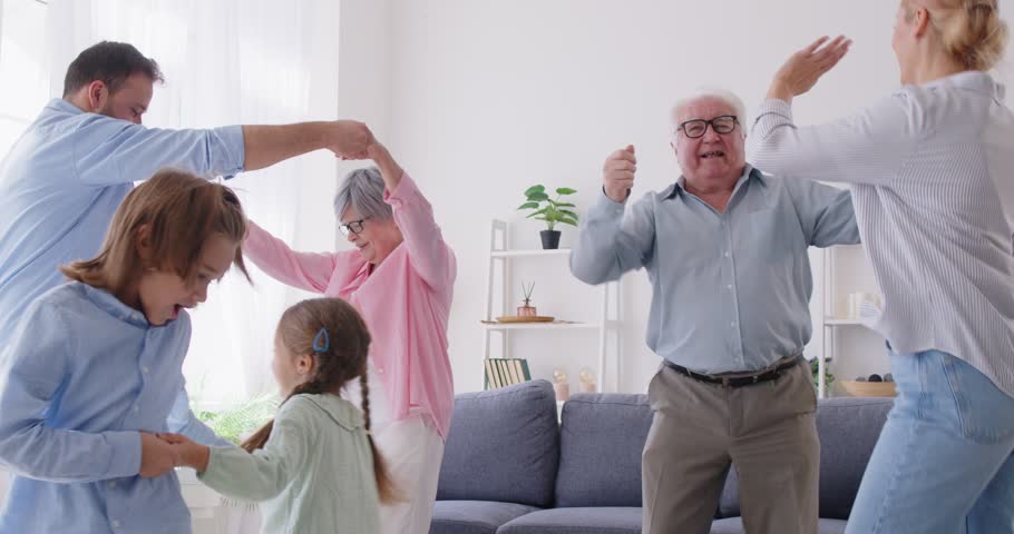 Family dancing together to music at home, enjoying a fun celebration. The shared leisure time fosters bonding and togetherness as they party and create joyful memories in a lively home atmosphere.