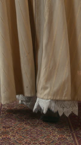 Vertical back view shot of priest in luxurious ceremonial vestment walking confidently along Catholic church heading to altar