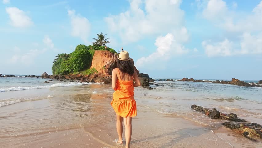 Excited Tourist smiley Woman Running Joyfully in Scenic Sri Lanka sunny beach.Parrot island popular landmark attraction. Mirissa coastline. Sri lanka travel sightseeing concept.