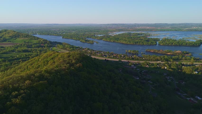 Aerial video from Apple Blossom Overlook Park showing green rolling hills and the Mississippi River at sunset with glowing sky and peaceful scenery.