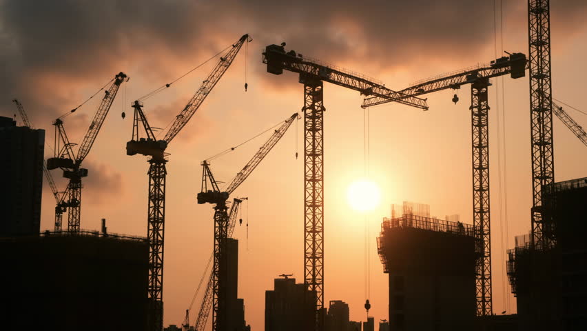 Tower crane and building construction site silhouette at sunset