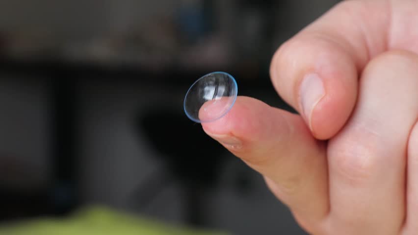soft contact lens balanced on fingertip with dark blurred background, symbolizing comparison between daily disposable and reusable vision correction options, concept of optometry, personal eye care 