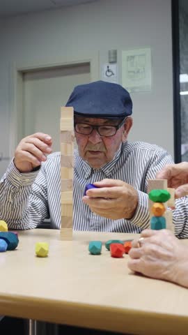 Elderly man and therapist playing with building blocks in slow motion