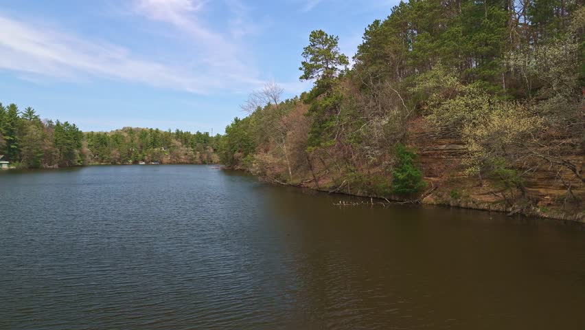 Drone video flying over Mirror Lake State Park in Wisconsin capturing Echo Rock’s scenic sandstone cliffs and calm lake reflection from the water.