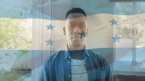 Man standing in living area, displaying translucent Honduras flag graphic with technology overlay. Patio, contemporary, digital, home interior, leisure, patriotism, lifestyle - Powered by Shutterstock - Get 15% off with code: PIKWIZARD15