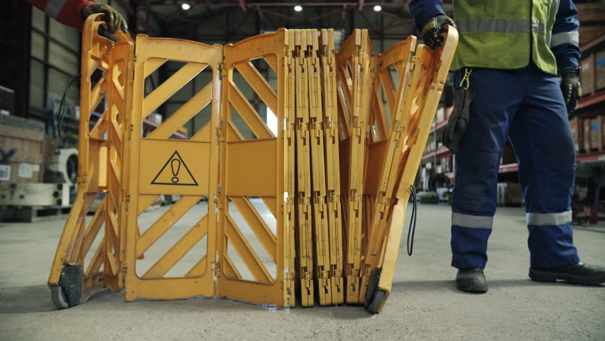 Workers setting up expandable safety barrier in industrial area