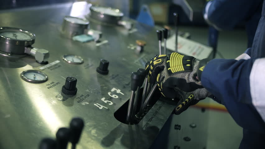 Worker operating oil drilling control panel with levers