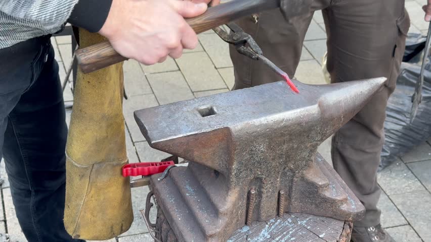 Blacksmith forging metal on an anvil manually
