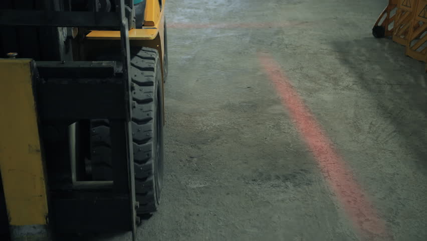 Forklift driving on marked floor inside warehouse