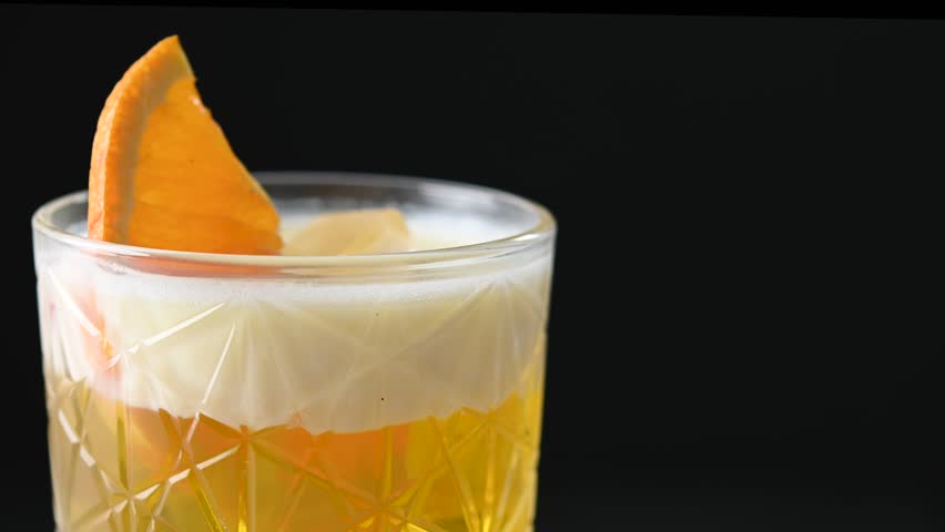 Rotating classic cocktail whiskey sour isolated on black background
