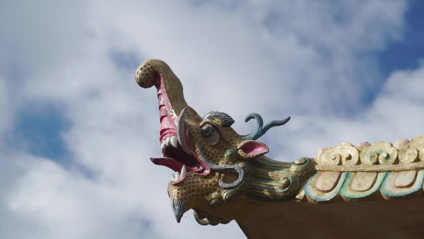 dragon head sculpture on buddhist pavilion roff against a cloudy sky in Ladakh