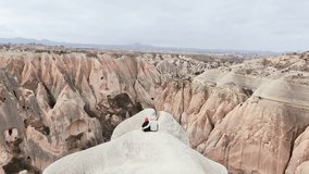 Aerial view Couple of tourists having fun sit together relax enjoy rocky formations red rose valley landscape in Cappadocia at holiday - Happy friends laughing together on vacation - People holidays - Powered by Shutterstock - Get 15% off with code: PIKWIZARD15