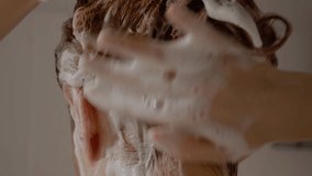 A woman is in the shower, lathering her hair with shampoo as she rinses off. She enjoys the warm water and foam to clean her hair thoroughly in a calming atmosphere. - Powered by Shutterstock - Get 15% off with code: PIKWIZARD15
