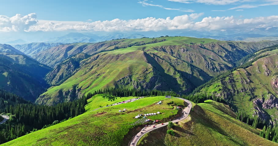 Aerial view of a winding road and green grassland with mountain natural landscape in Xinjiang. Duku highway is the most beautiful highway in China.