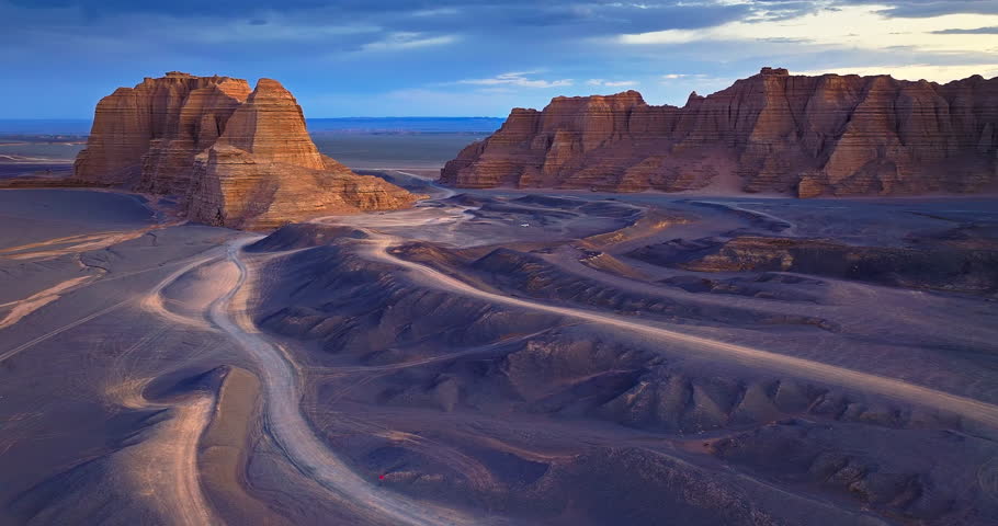 Yardang landform mountain with tire tracks at dusk. Famous Dahaidao no man's land natural landscape in Xinjiang, China.