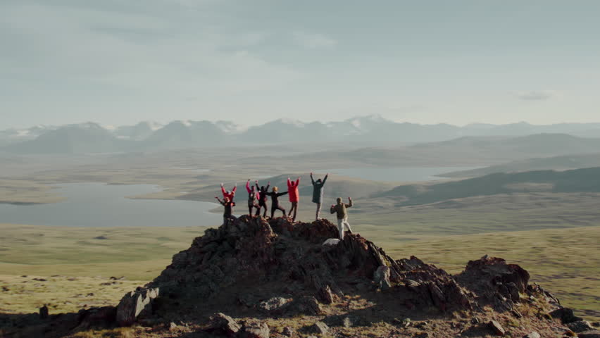 Drone view of a large group of diverse tourists celebrating reaching the summit in the Altai Mountains