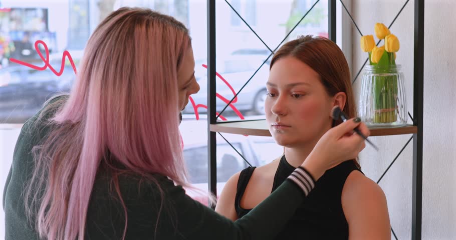 Makeup artist applies cosmetics with a special brush on the cheekbones and cheeks of the model. Close-up. Professional makeup