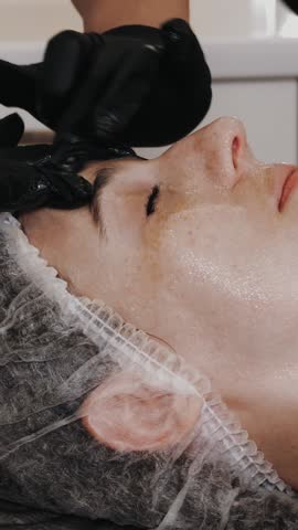 Beauty therapy. facial massage. Cosmetology skin care. close-up. woman is getting cosmetic facial scrubbing procedure, tonied and clean skin, at beauty clinic. anti-aging. facial rejuvenation.
