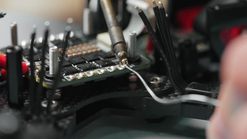 Technician soldering components onto circuit board of disassembled fpv drone - Powered by Shutterstock - Get 15% off with code: PIKWIZARD15