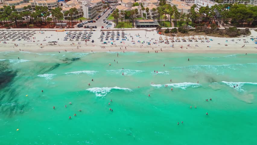 Aerial view of Platja de sa Coma beach in Mallorca, Balearic Islands, Spain. Stunning white sand beach with turquoise waters, surrounded by a beautiful resort on Majorca island during summer.