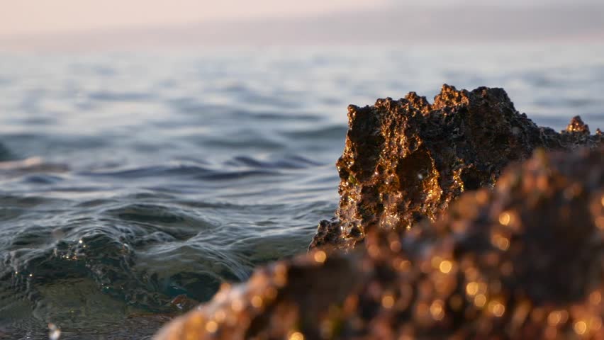 Sea waves motion and rock detail at sunset, slow motion