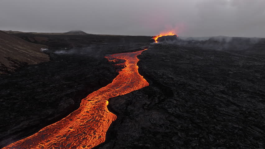 Aerial drone view over river of molten hot lava erupting from the Litli-Hrutur Iceland volcano and flows through dark rock. Abstract pattern formed by a lava river. Dangerous disaster.