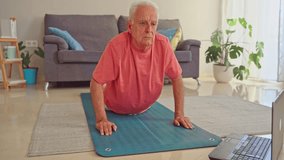 Video of senior man exercising on fitness mat at home following an online fitness class on laptop - Powered by Shutterstock - Get 15% off with code: PIKWIZARD15