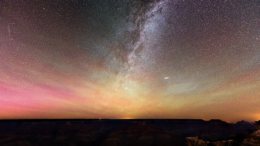 The Milky Way and northern lights dance spectacularly over the Grand Canyon in a breathtaking time-lapse, blending cosmic wonders with rugged natural beauty.