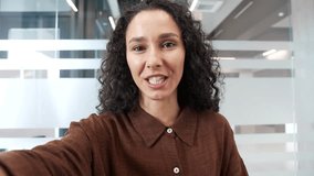POV Young smiling businesswoman talking on video call using mobile phone at a workplace in business office. Happy woman worker looking at camera taking selfie, greeting, waving, communicating remotely - Powered by Shutterstock - Get 15% off with code: PIKWIZARD15