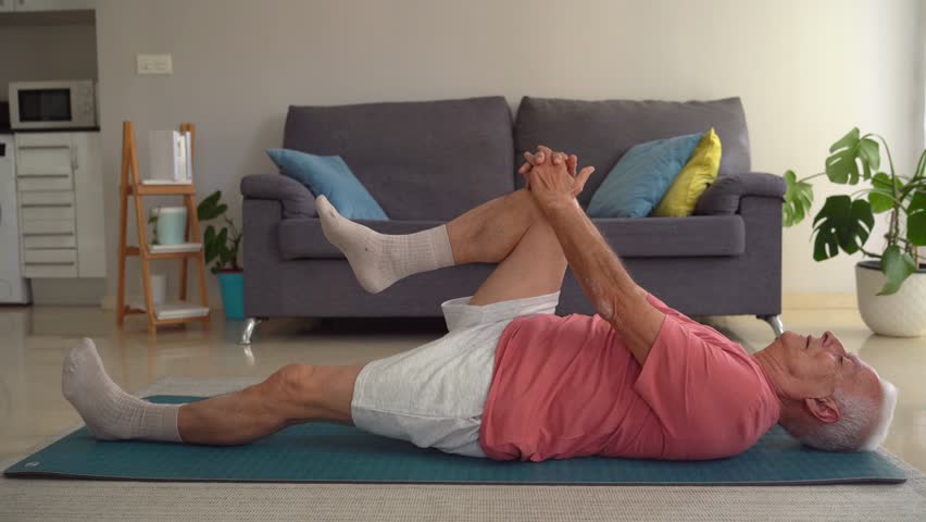 Video of elderly man doing legs stretching exercises on yoga mat at home