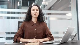 Young businesswoman relaxing breathing deeply while sitting at a desk at a workplace in a business office. Calm happy female employee resting with her eyes closed. Joyful woman took a break from work - Powered by Shutterstock - Get 15% off with code: PIKWIZARD15