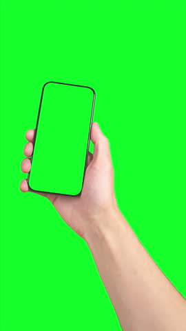 Man swipes left and right on smartphone with green screen and tracking marks, held in hand against solid chromakey background, ideal for screen replacement.