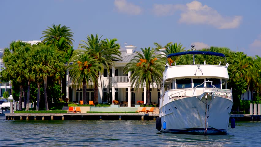 8k video boat in water. Luxury mansions with palms in the background