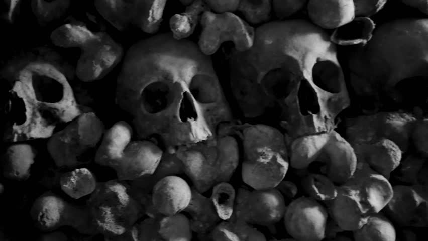 Vintage film-stylised black and white Video of many Human Skulls and Bones arranged in rows in Catacombs.