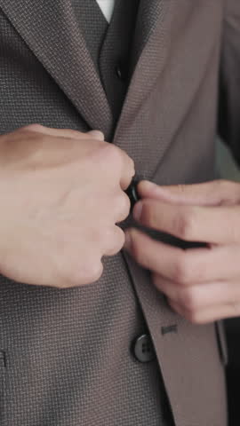 Groom adjusting his suit jacket before the wedding, A close-up image of a groom's hands adjusting the button on his suit jacket.